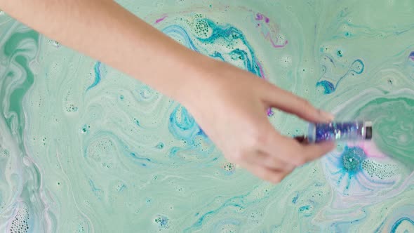 Pouring Blue Glitter Into Water with Dissolved Bath Closeup