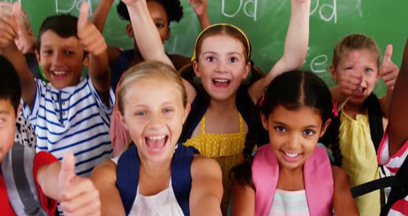 School kids showing thumbs up in classroom