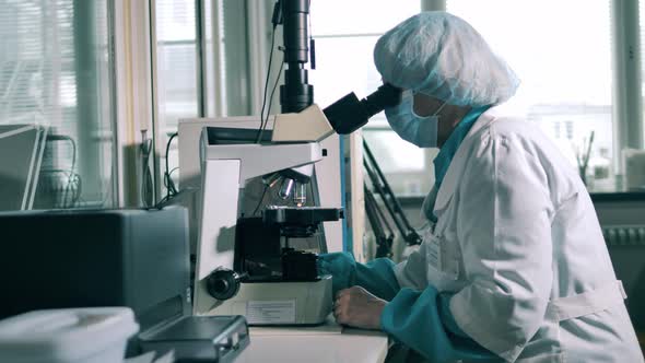 Female Researcher Is Using a Microscope To Examine a Pill