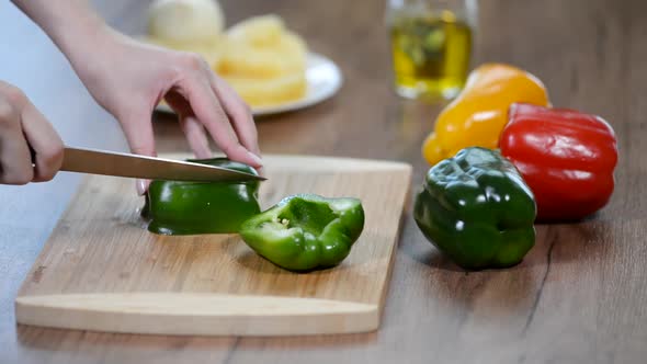 Women's hands cut green pepper on a wooden Board