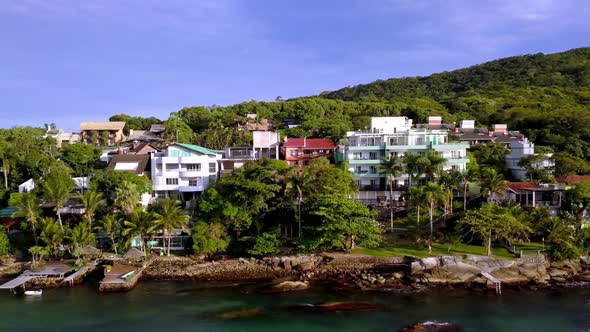 Aerial dolly right shot of a morro with houses and revealing the Praia da Sepultura in Brazil