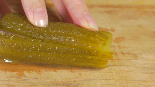 Pickled cucumber cutting on smaller pieces  with knife on wooden board 4K 2160p UHD panning footage 
