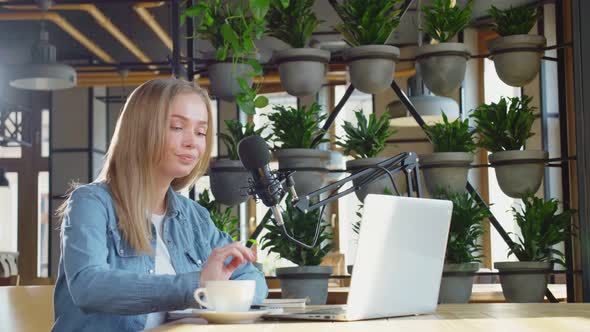 Young Cute Woman Sitting at Table and Working in Laptop