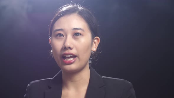 Close Up Of Asian Speaker Woman In Business Suit Speaking In The Black Screen Studio