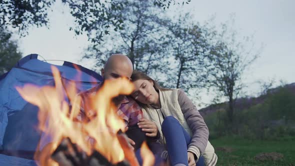 Happy Young Couple Sitting by the Fire in a Tent 