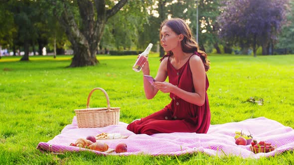 Happy Woman with Smartphone on Picnic at Park