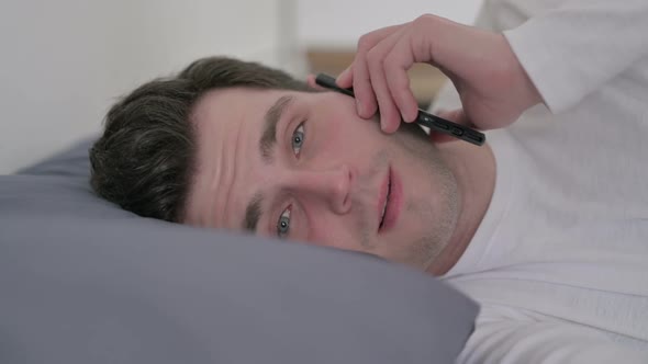 Man Talking on Smartphone While Sleeping in Bed Close Up
