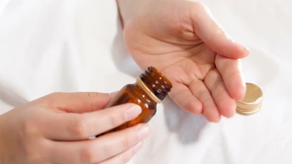 Closeup Slow Motion Footage of Woman Pouring Tablet on Hand From Glass Bottle Container