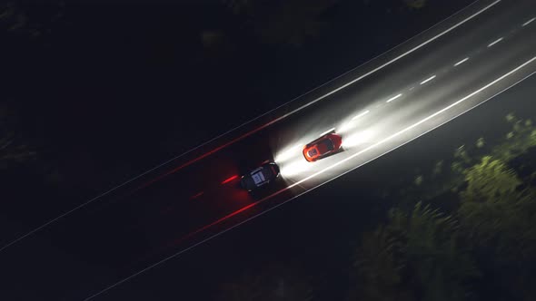 Night scene of a police chase on a curvy road with trees flashed by headlights.