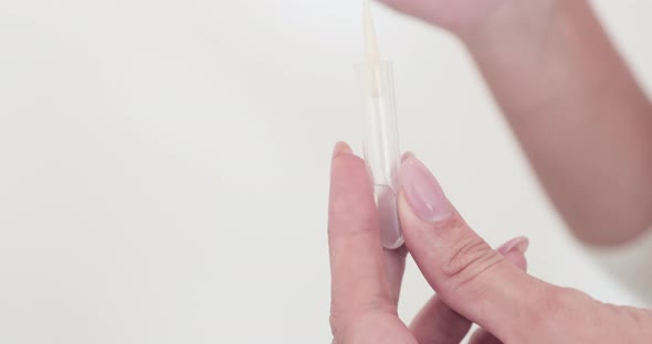 A Person Placing The Cotton Swab Into The Medical Plastic Applicator Tube - Covid-19 Swabbing Method