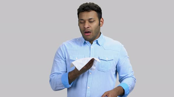 Young Darkskinned Man Blowing His Nose in a Handkerchief