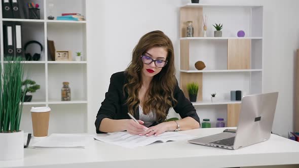 Businesswoman in Glasses Sitting at Her Workplace in Contemporary Office 