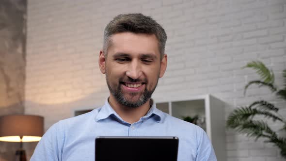 Close Up Smiling Man Trader Looks Tablet Analyzes Quotes on Stock Exchange