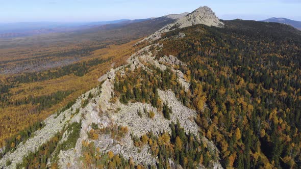 Aerial view of the mountains with rocks and beautiful autumn woods on the slopes