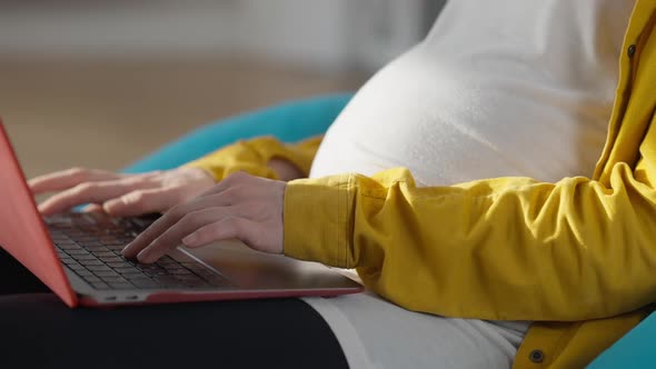 Hands of Pregnant Young Woman Typing on Laptop Keyboard Indoors