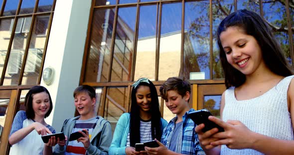 Group of school friends using mobile phone outside school