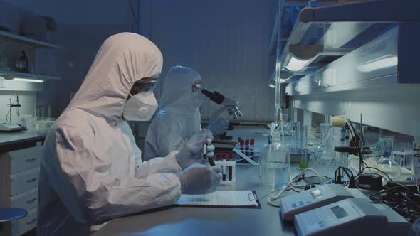 Epidemiologists in Protective Coveralls Working with Blood Samples