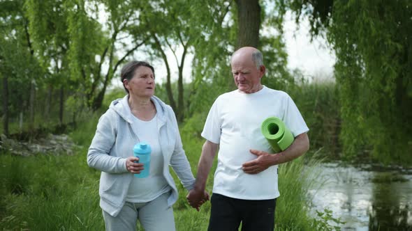 Elderly Married Couple with Bottle of Water for Sports Nutrition and Yoga Mat Go Hand in Hand After