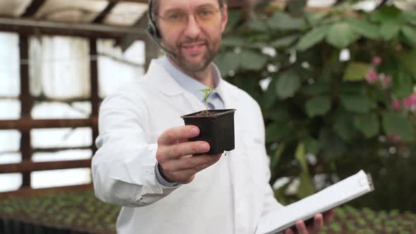 Scientist Shows Seedlings in Large Greenhouse