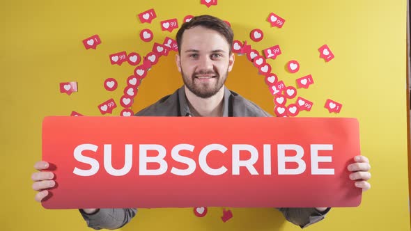 Positive Person Smiling Asks you to Subscribe Holding a Sign in His Hands