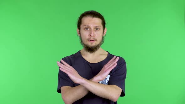 A Serious Young Man Crosses His Arms in a Stop Gesture and Says Stop and No