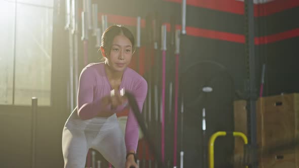 Asian young active athlete or sport woman using battle Rope workout exercise to lose weight in gym