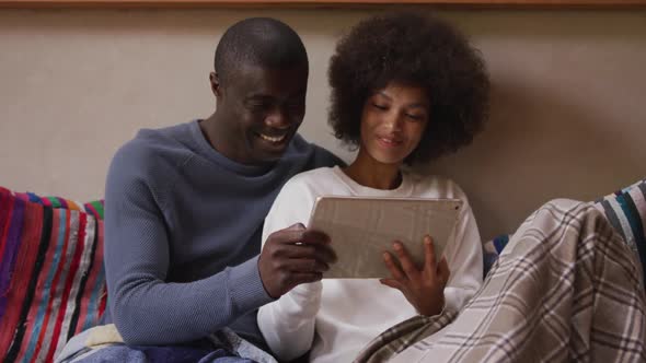 Couple using digital tablet in living room