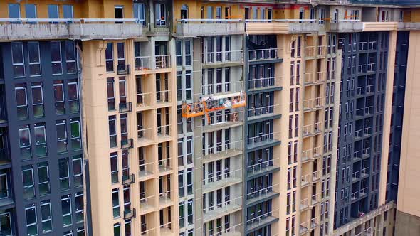 High-rise architecture under construction. Workers on the outdoor lift doing the beautiful facade