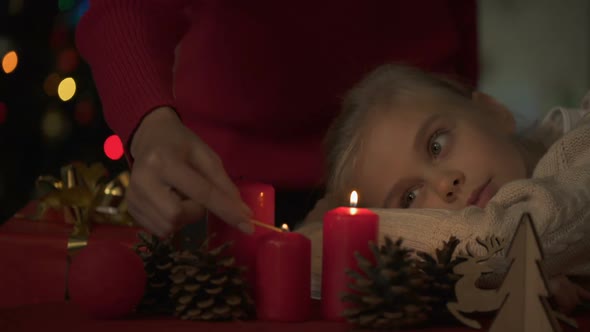 Little Daughter Looking How Mother Lighting Christmas Candles, Belief in Miracle