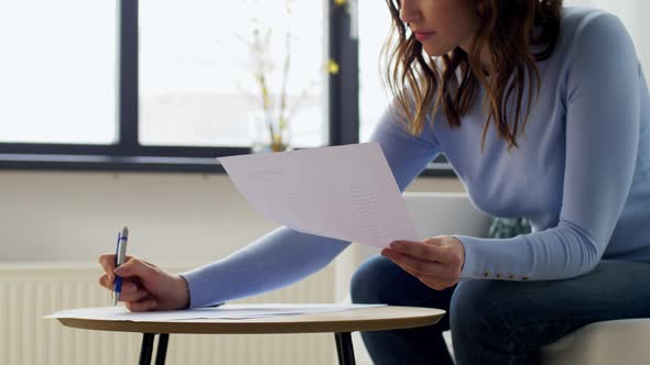 Woman with Papers and Calculator at Home