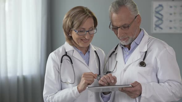 Female and Male Physicians Looking at Tablet With Admiration, App for Medics
