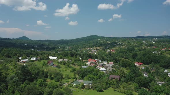 Aerial View of Village Houses in a Mountain Valley Against a Blue Sky with Occasional Clouds