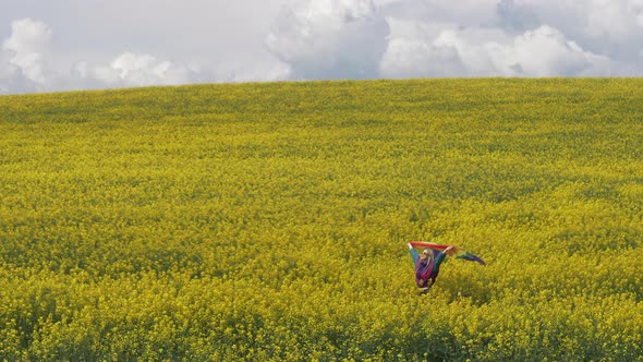 Female with LGBT rainbow flag on yellow rapeseed field in spring