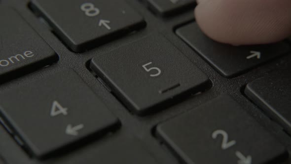 The Finger Presses a Button with a Number on the Keyboard