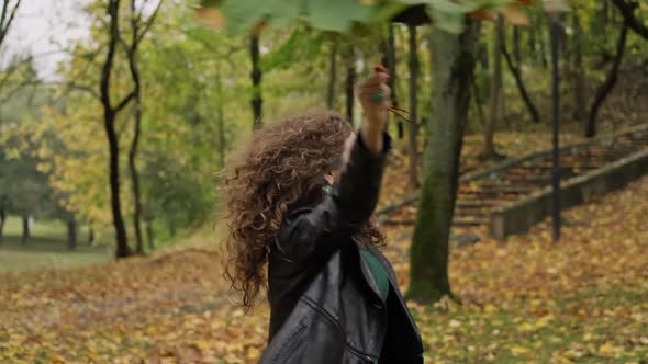 Attractive Brunette Woman Whirling with Umbrella From Leaves in Autumn Park