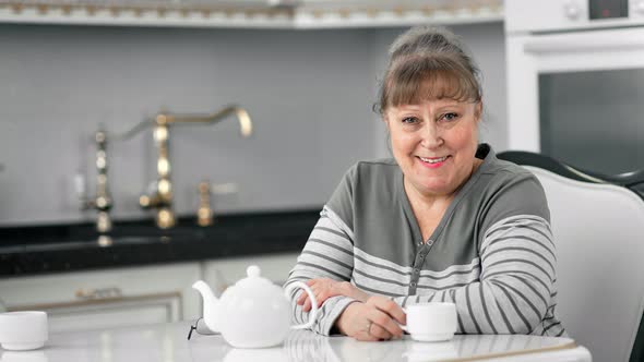 Happy Pleasant Middle Aged Woman Enjoying Tea Smiling Looking at Camera