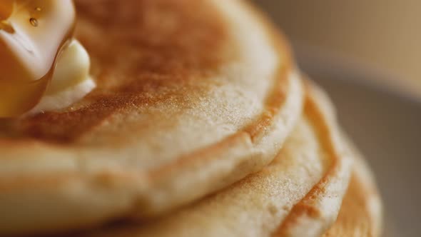 Pouring honey on stack of pancakes. Slow Motion.