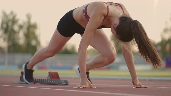 Caucasian Young Brunette Woman Shit for a Run in the Stadium Comes Up to the Running Sides and