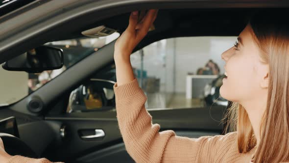 Pretty Young Lady Examining Interior of Luxury Car While Sitting Inside