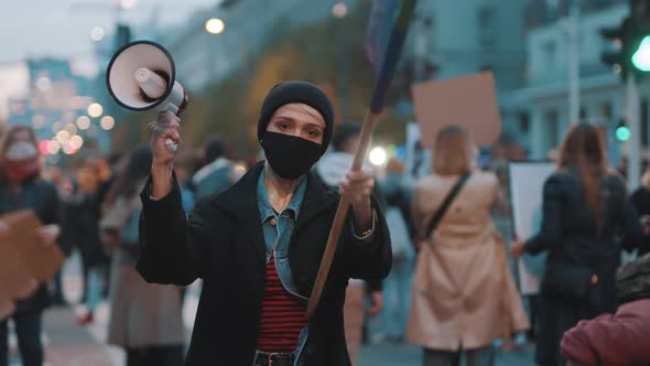 Woman with Face Mask Holding Megaphone and Rainbow Flag. Demonstration Against Dicrimination 