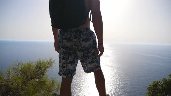 Male Hiker Standing on Peak and Victoriously Raising Hands Rejoicing Achievement or Success