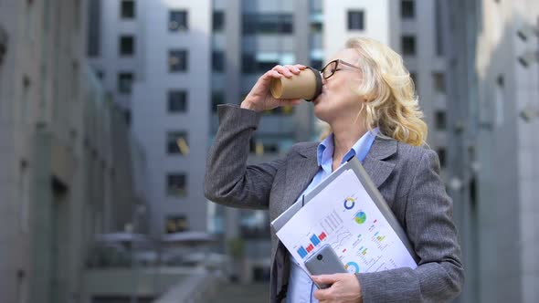 Mature Business Lady Documents in Hand Drinking Coffee and Smiling, Inspiration