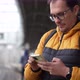 Caucasian Mature Man in Glasses and with Backpack Stands at Train Stop and Tapping on Mobile Phone - VideoHive Item for Sale