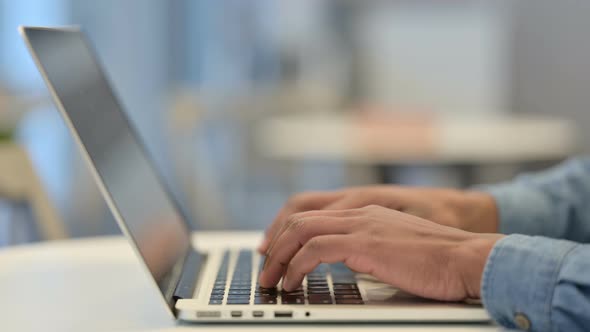 Hands of African Man Typing on Laptop Keyboard Close Up