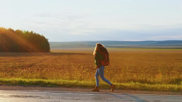 Girl Traveller with Backpack is Walking on Road