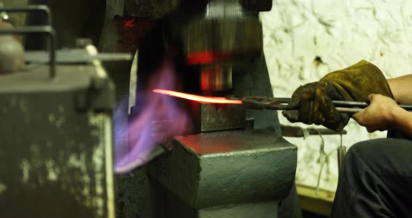 Bladesmith working with hot blade at hydraulic forge hammer