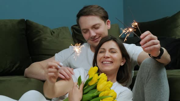 Happy Young Couple Celebrating Love with a Sparklers in Hands Yellow Tulips