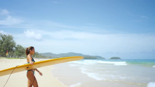 4K Portrait of Asian woman in swimwear holding surfboard walking on the beach in summer sunny day.