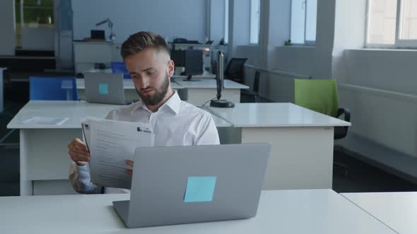 Young Man Looks Through His Paper Work in Company