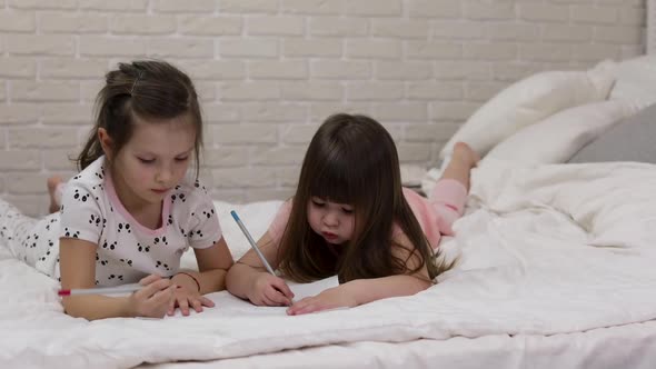 Kids Drawing Pictures While Lying on Bed